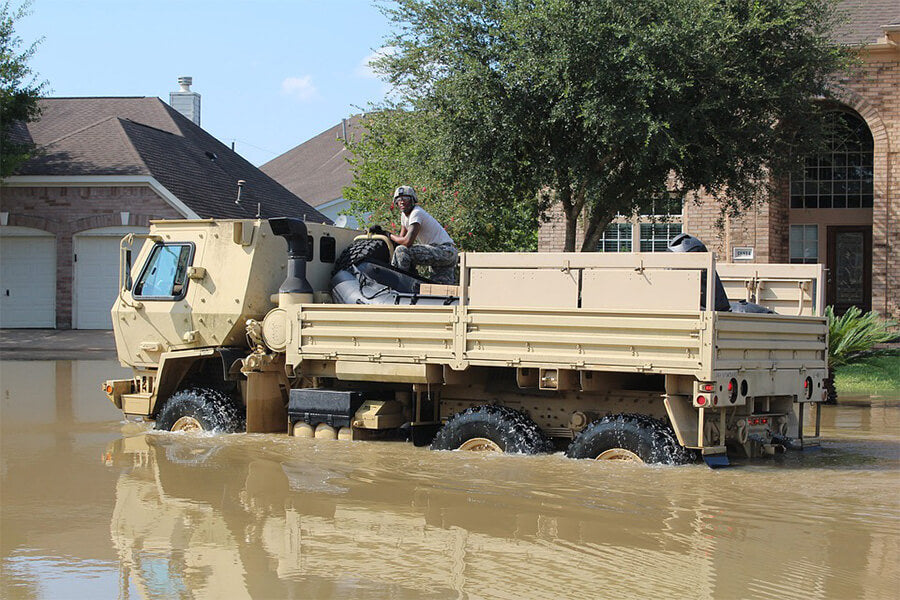 Military man sitting in tank in a flooded street