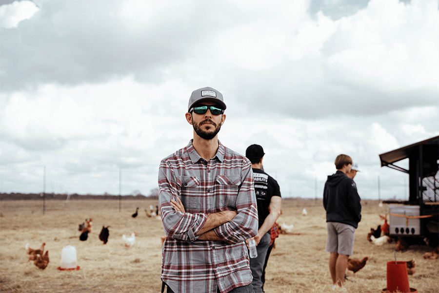 Man standing with arms crossed in open field 