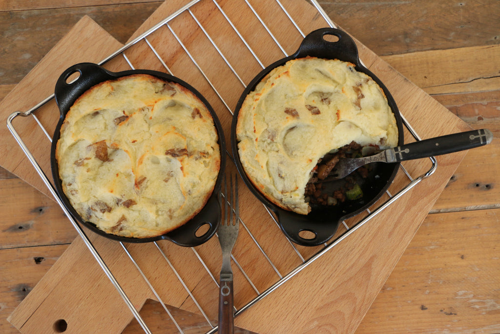 A close-up image of two skillets sitting on a cutting board. Within the skillets is the result of this recipe - EPIC Beef Tallow Skillet Shepherd's Pie.