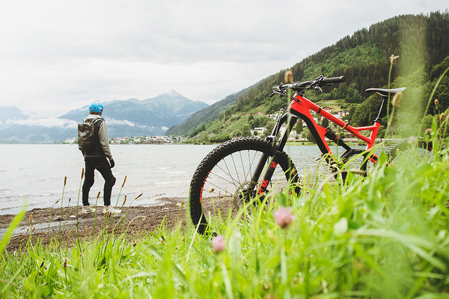 Mountain bike and grass in foreground with man and mountains in background 