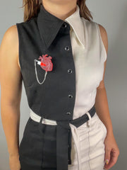 Woman wears a black and white jumpsuit with Vinca's Heart of Aghast Brooch.