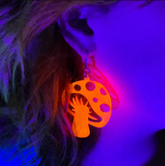 Transparent neon Shroom to Grow mushroom fish hook earrings glowing under black light.