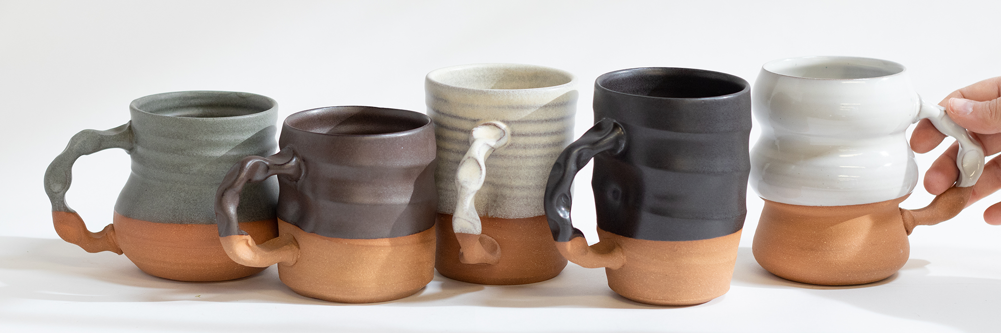 5 handmade mugs in varying neutral colors on a white background