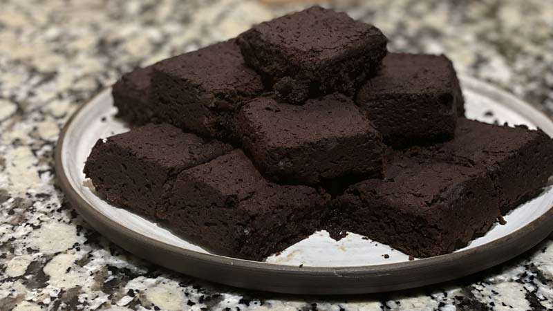 white handmade pottery plate full of carob aip gluten free brownie squares on a granite countertop