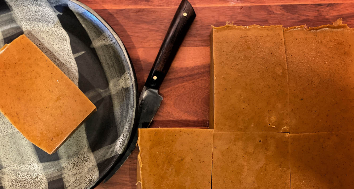 pumpkin pie protein bars for AIP and Paleo friendly diet inflammation protocol on a cutting board after being sliced. On the right side is a handmade plate by Rebecca of Gravesco Pottery and a handmade knife by Ash Blaeds of Indianapolis, Indiana