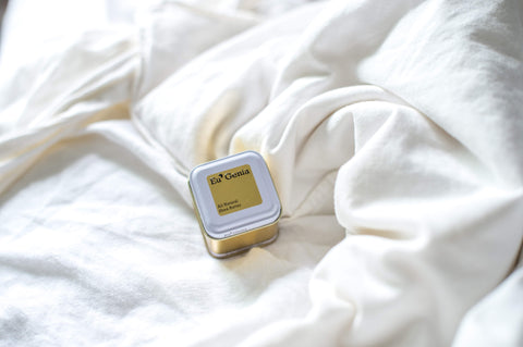 Small tin resting on white bedsheets