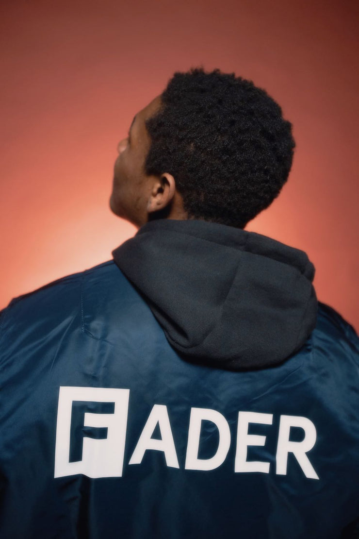 男子背部穿着FADER x Alpha MA海军飞行夹克与FADER的标志
