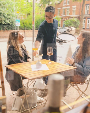 Garry serves a glass of orange wine to happy guests enjoying the outdoor seating at Reserve Wines in West Didsbury