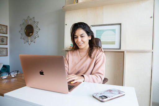 A woman working on a laptop computer with a Lori Bed murphy bed in the background