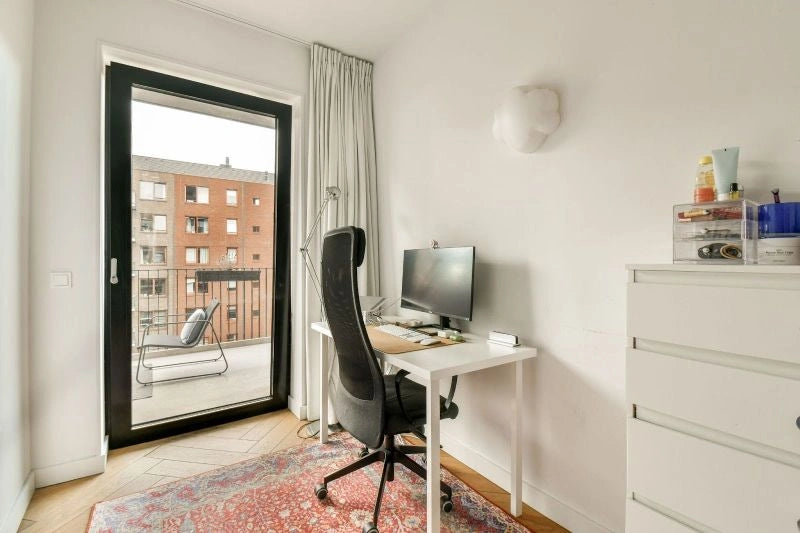 A small but comfortable desk chair positioned in front of a simple desk, offering a productive workspace with a view