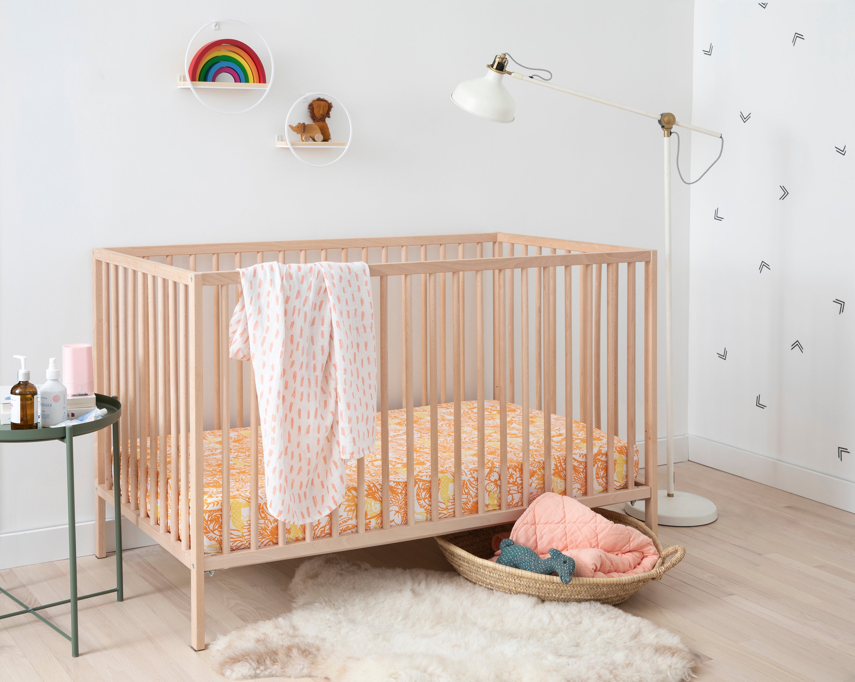 Brooklinen's Crib Sheet Set in "Jungle in Orange," paired with the Baby Quilt and Swaddle in "Blush."