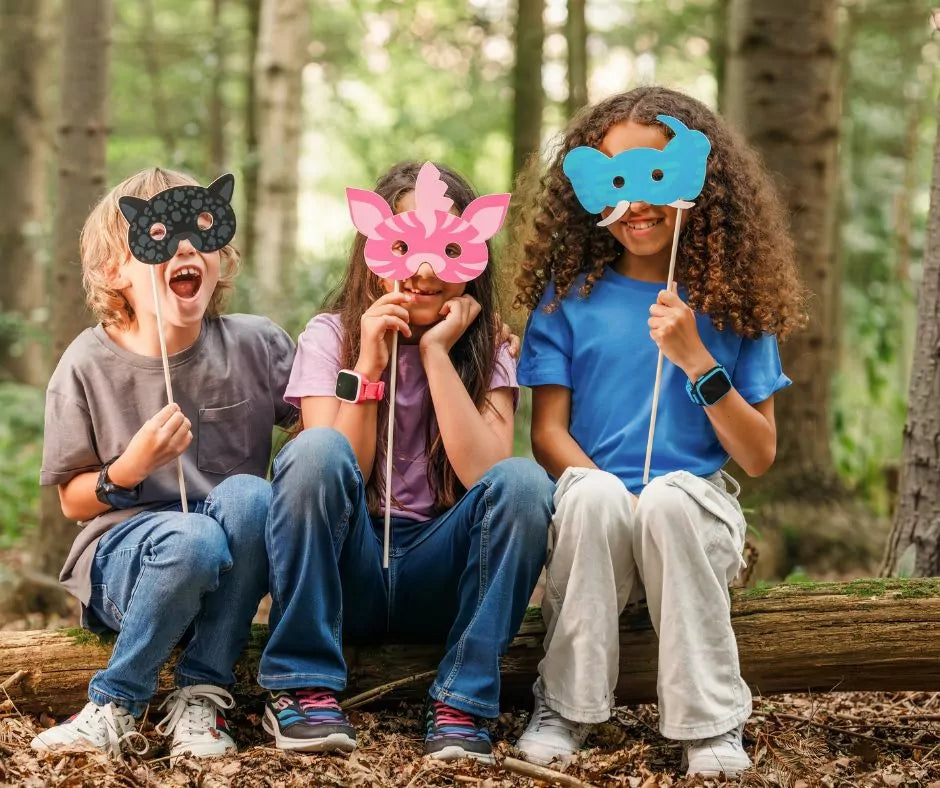 Kolme lasta metsässä pitämässä eläinnaamioita, ranteissa Xplora XGO3 Jungle Edition kellopuhelimet