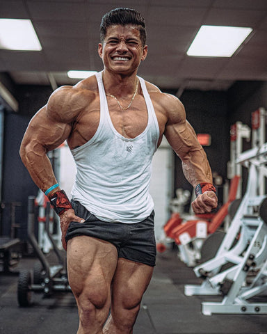 aesthetic bodybuilder wearing tank top and shorts in gym