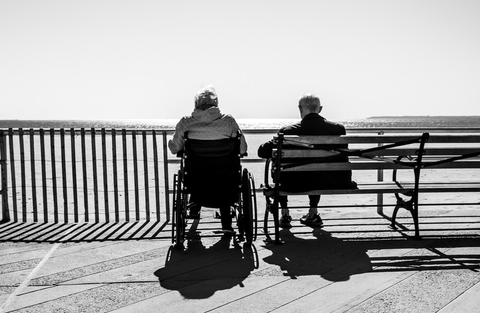 a person sitting in a wheelchair next to a bench