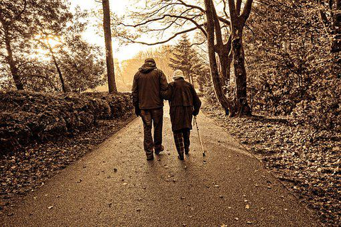 a man assisting an elderly person to walk