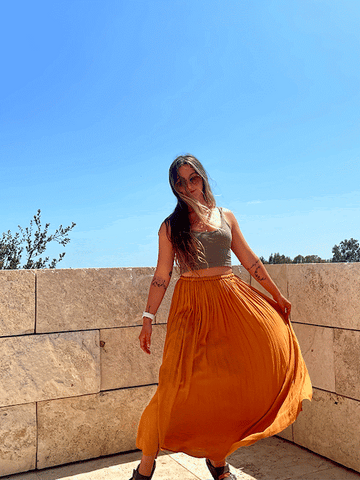 A gif of a girl twirling around on a balcony in a long skirt.