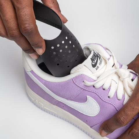 a hand pinching the right crease shield guard and inserting it into the shoe