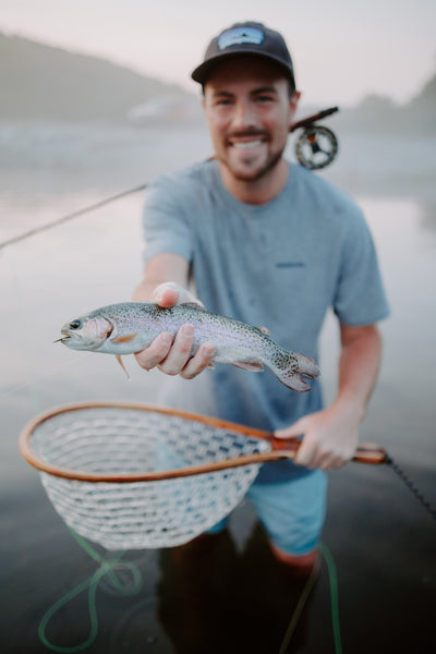 In this image, from Moonshine Rods, an angler holds a rainbow trout.