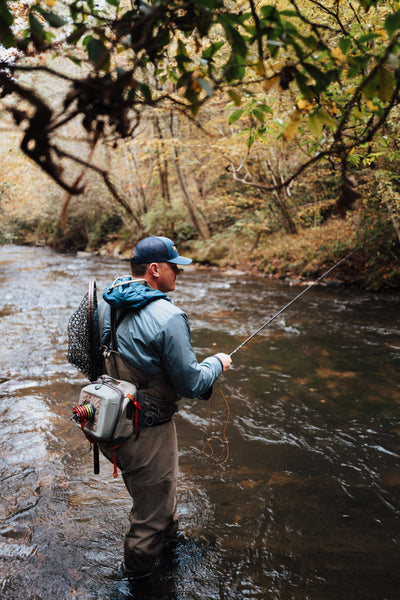 In this image, from Moonshine Rods, an angler is standing in the river holding a fly rod.