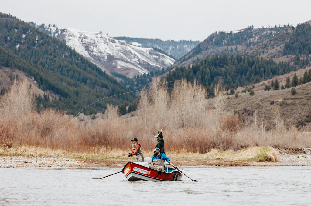 This image shows three anglers fly fishing from a drift boat.