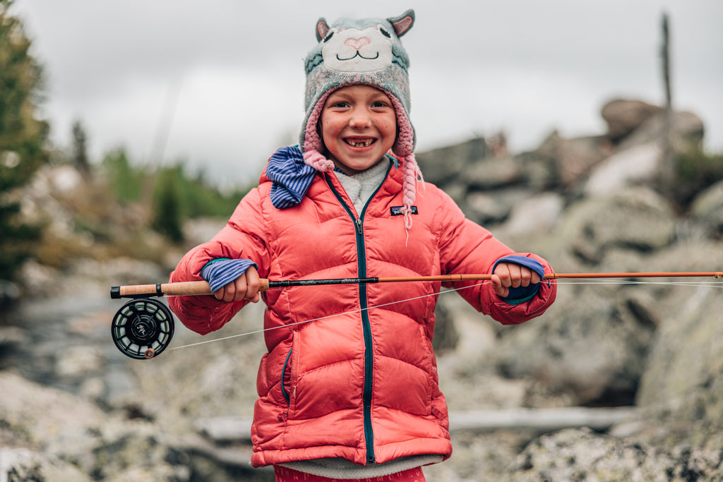 In this image, from Moonshine Rods, a little girl holds the all-new Revival S-Glass fly rod.