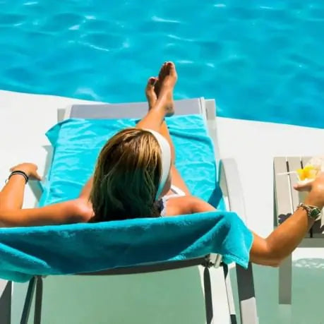 Female relaxing poolside in a chaise lounge with a drink