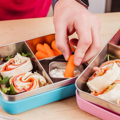 Person eating carrots and ranch dressing out of stainless steel bento box dip container