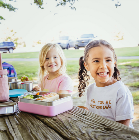 2 children at picnic table with bento box