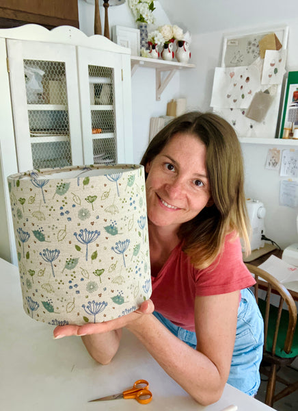 Charlotte Macey holding a floral print lampshade with cow parsley in her home studio.