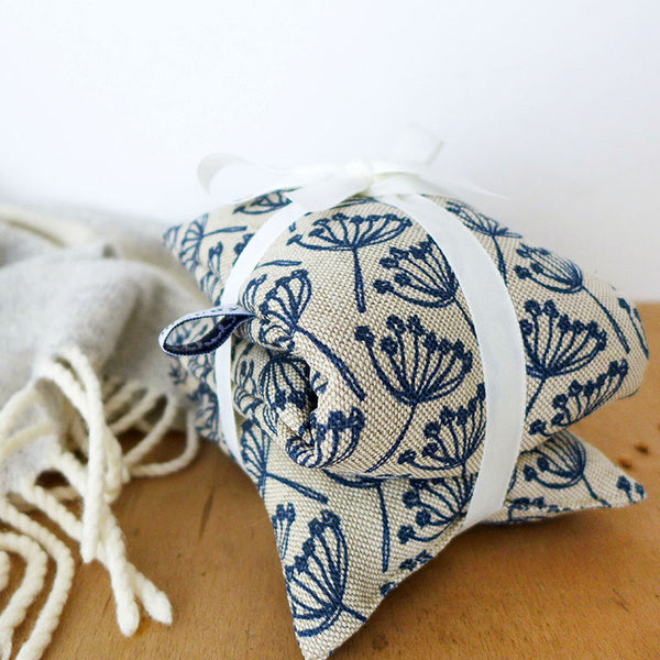 floral navy cow parsley long wheat heat bag with ribbon and next to a cosy blanket