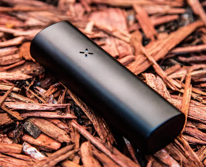 The PAX Mini Dry Herb Vaporizer on a green grass background