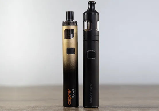 Two vape pens on a wooden table with a grey background.