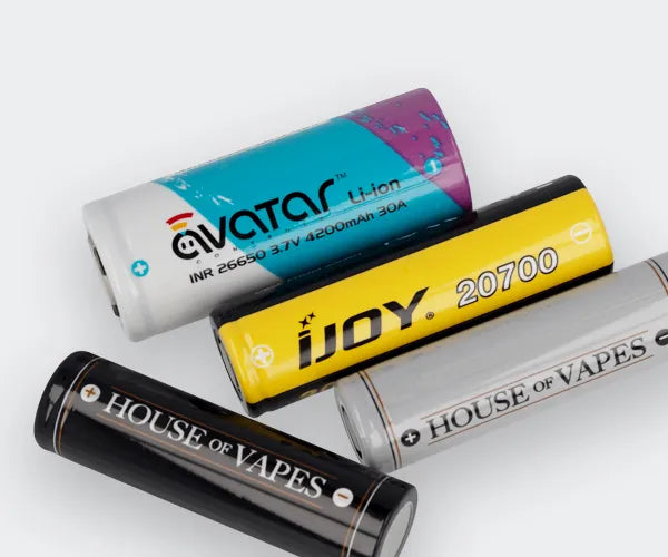 Four different size vaping batteries on a grey background.