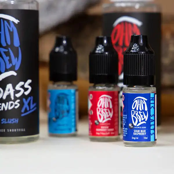 Five e-liquid bottles on a white table, all in different sizes.