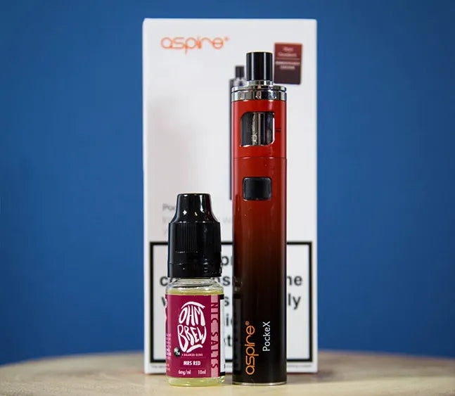 An Aspire PockeX AIO vape kit on a wooden table with a 10ml bottle of e-liquid beside it.