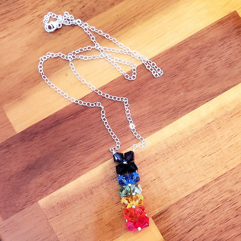 Rainbow Crystal Candy Rock necklace laying on wooden counter top- Alexa Martha Designs