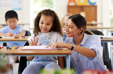 Teacher, learning and helping girl in classroom for knowledge