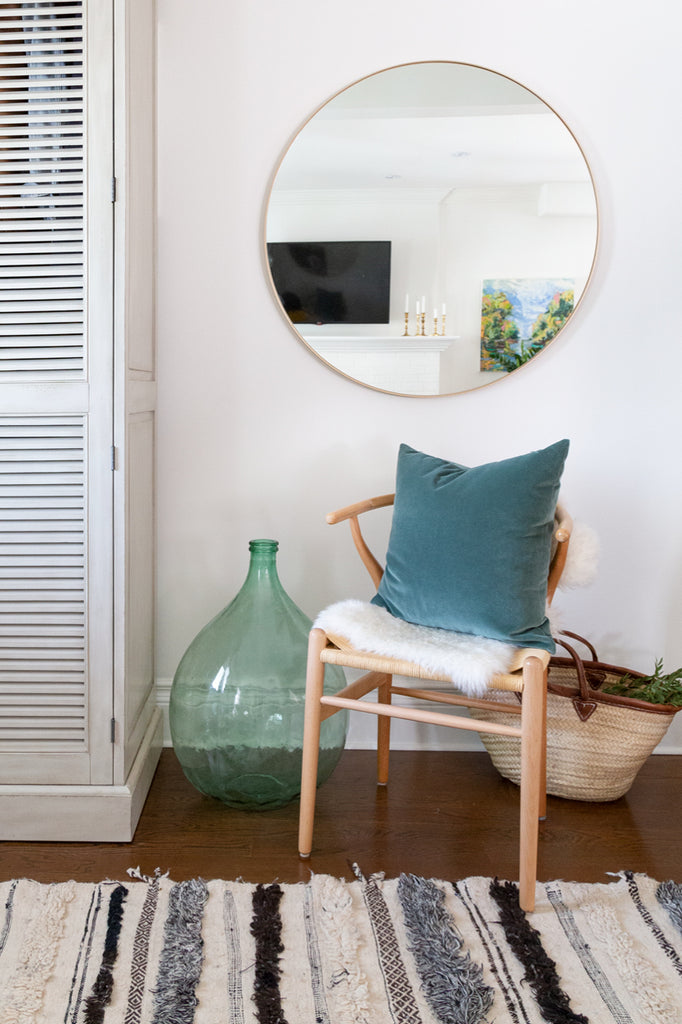 Adena Leigh's open-concept entryway with wishbone chair, round brass mirror and Tonic Living pillows