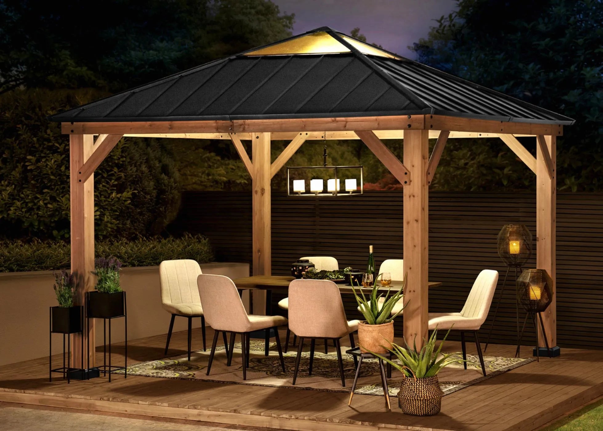 Wooden gazebo with outdoor furniture and lighting at night