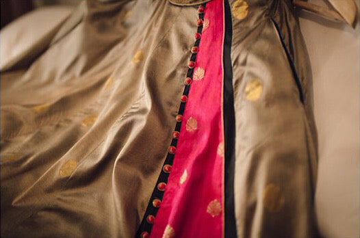 A lehenga skirt made in a handwoven silk fabric in grey gold colour with a pop of pink and potli button detailing