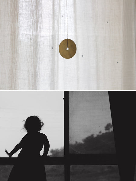 Collage of two images in black and white indicating memories of childhood. The top image has white curtains at the back and a disc with a star cutout hanging in front. The bottom image is of a child peering out of the window