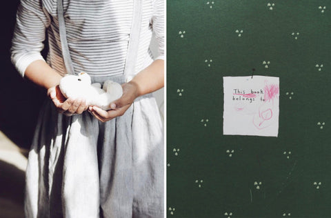 A collage of two images part of a photo story on memories of childhood by photographer Nirmala Mayur Patil. The image on the left is of a little girl holding a soft toy in her cupped hands like holding a baby. She is wearing black and white striped tee with a grey pinafore dress on top. The image on the right is of a green book with a piece of paper on top that reads 'This book belong to' in a child's handwriting.   