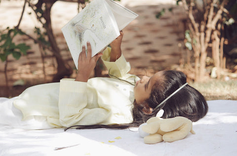 A little girl lying down and reading BERTOLT by Jacques Goldstyn