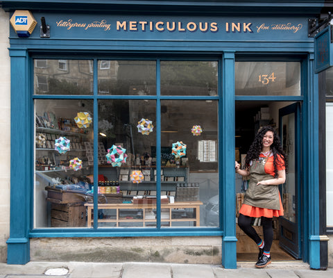 A blue shop front with Athena standing in the open doorway.