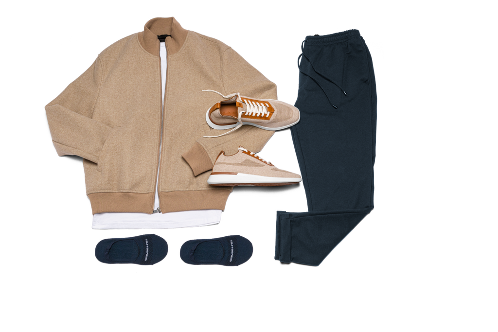 Mocha shoes laid out on white surface with jacket, pants, socks, and shirt. 