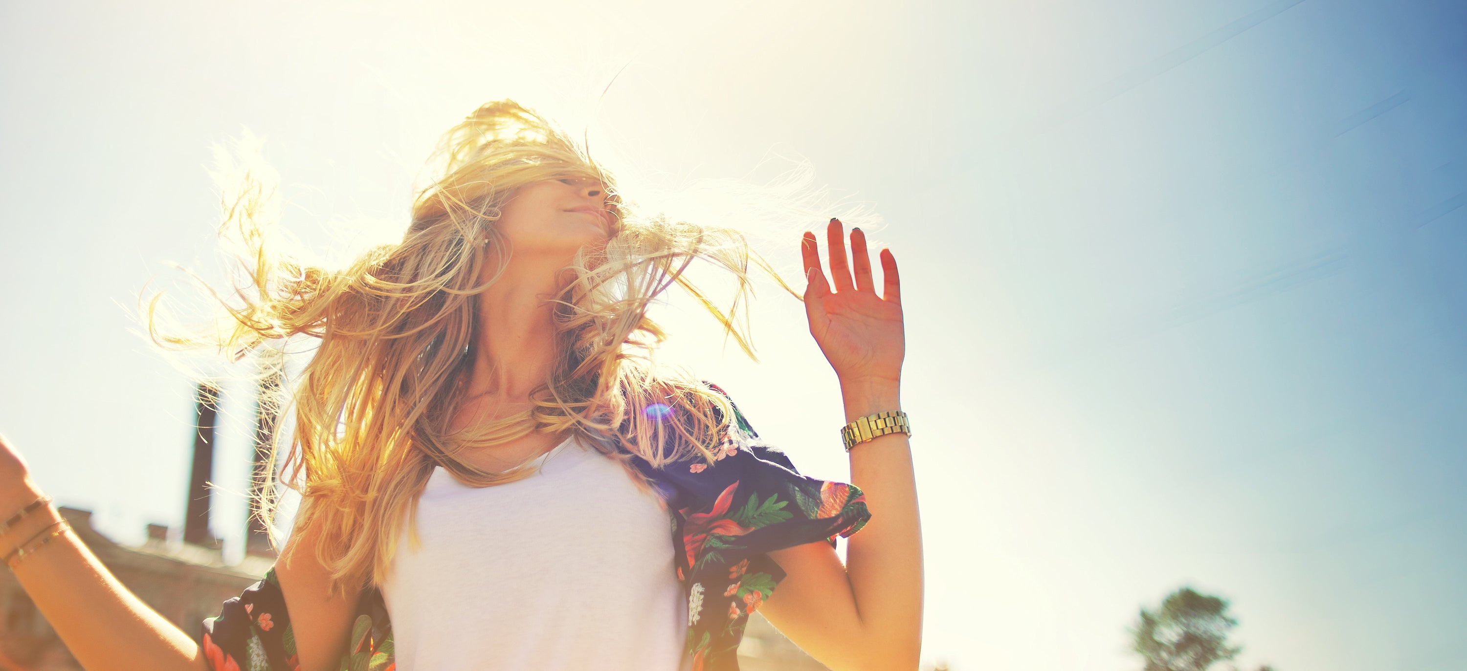 young woman with long blonde hair in white tank enjoying sunshine