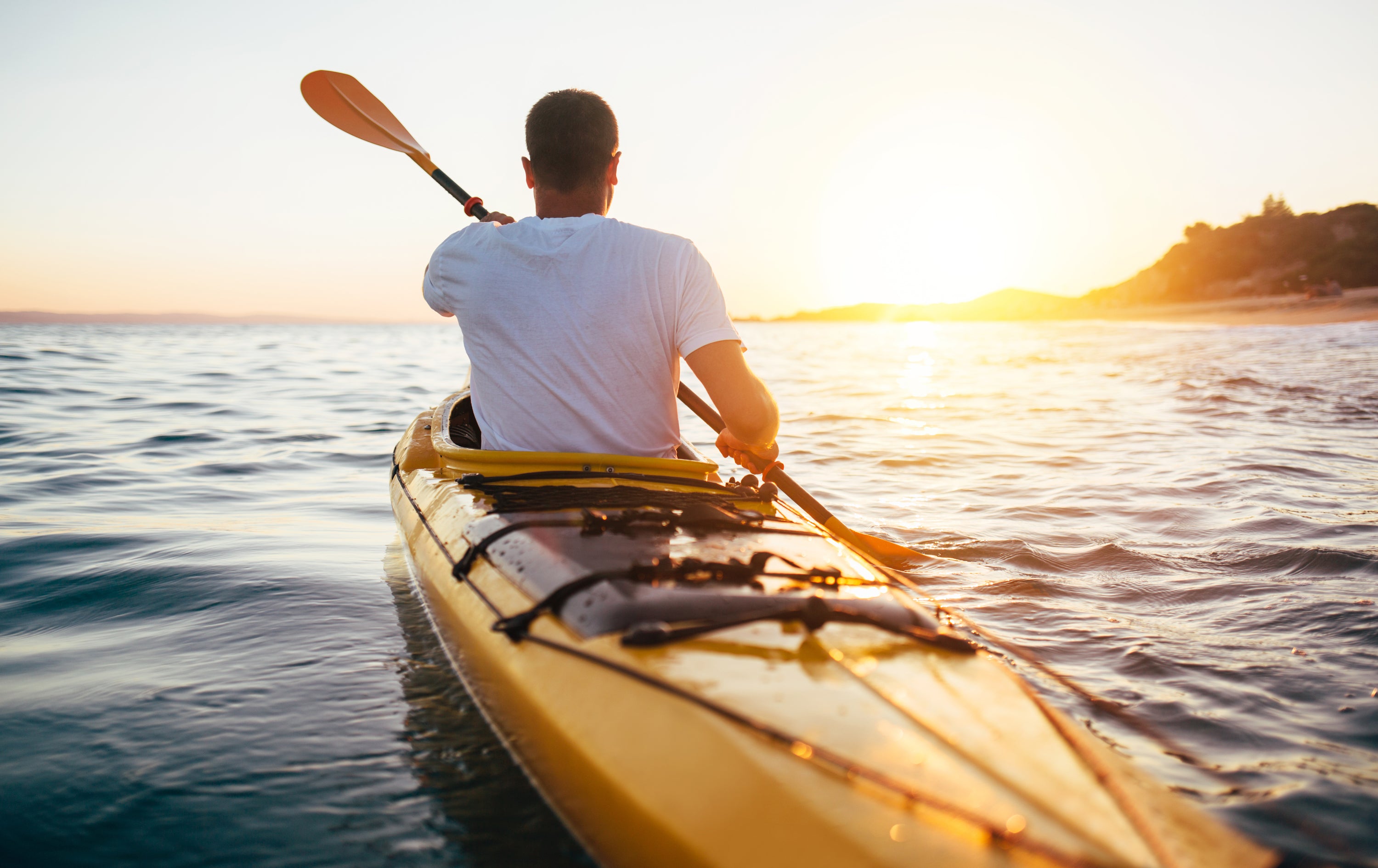 man kayaking on lake at sunset