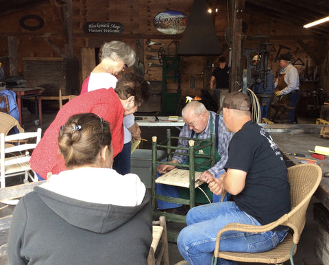 Students paying close attention to the Lenton Williams as he shows the correct technique to cane a chair bottom.