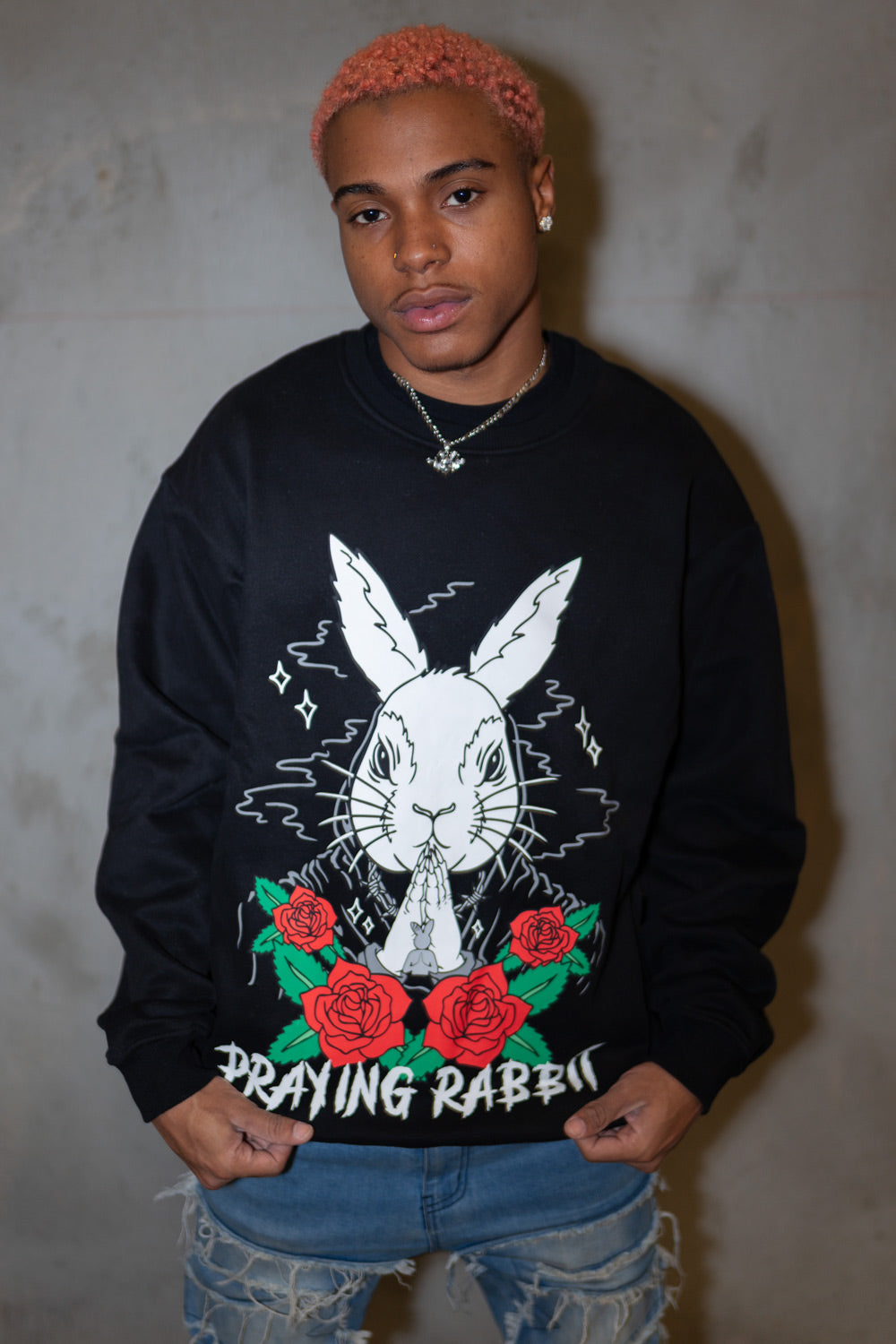 model wearing black crew neck with praying rabbit design