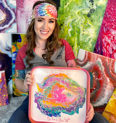 woman with dark hair wearing tie dye headband and colorful art in front of her